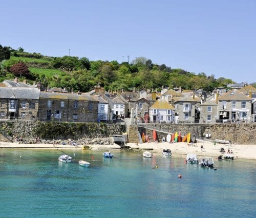 Colourful seafront cottages and fishing boats in Mousehole Harbour.