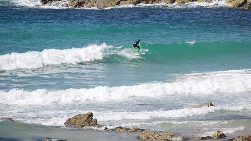 Surfer riding a small wave at Fistral Beach.