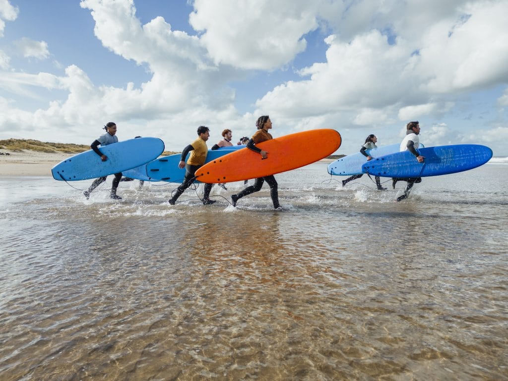 A shot of a medium group of people walking with surfboards on the beach at Amble