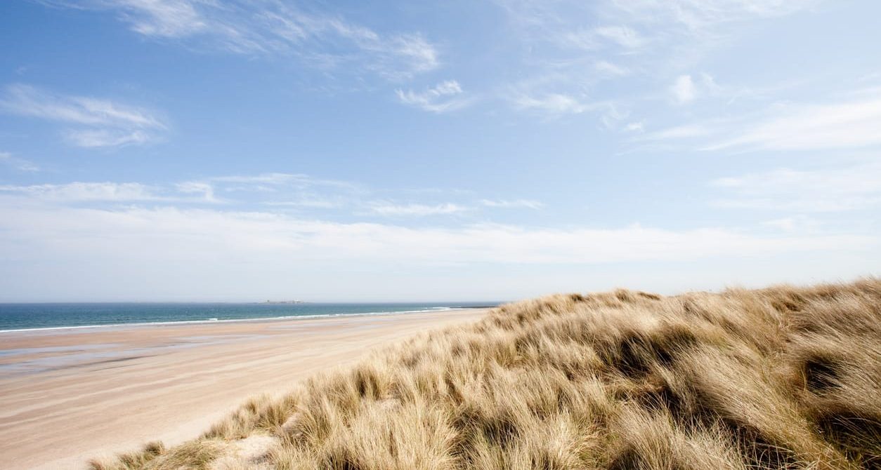 Northumberland beach landscape with waves and rolling dunes at sunrise