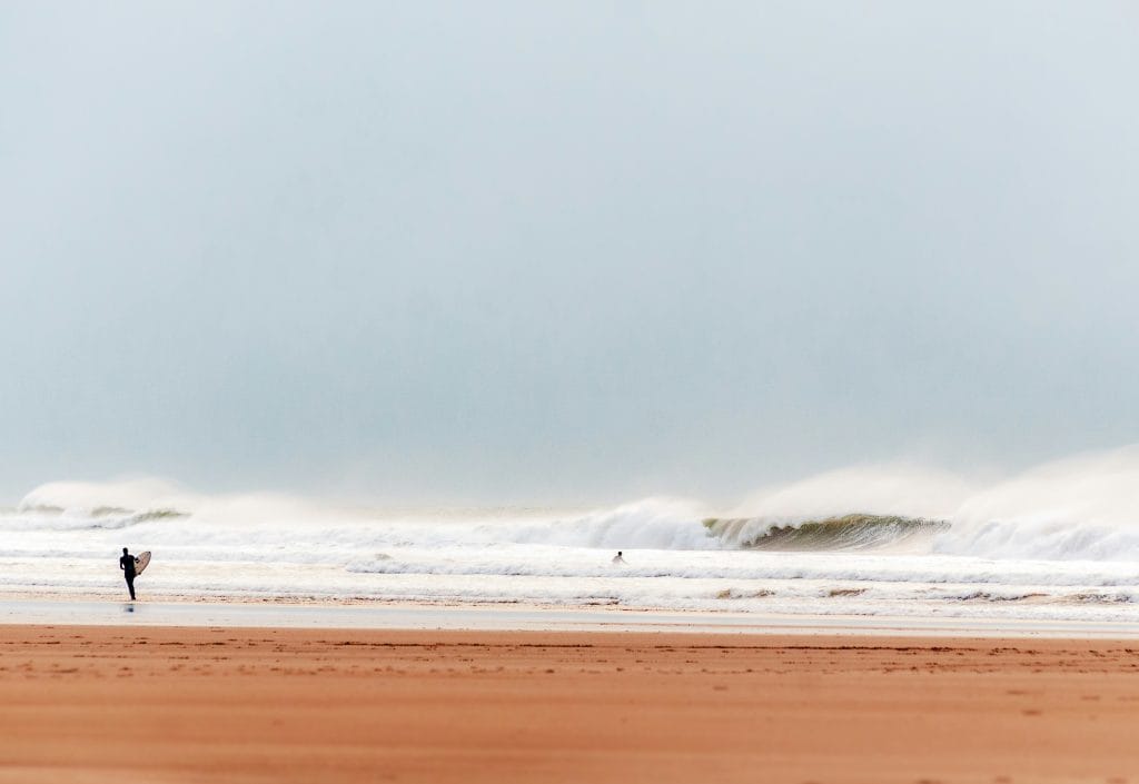 Surfers at Croyde Beach with waves rolling in behind them.