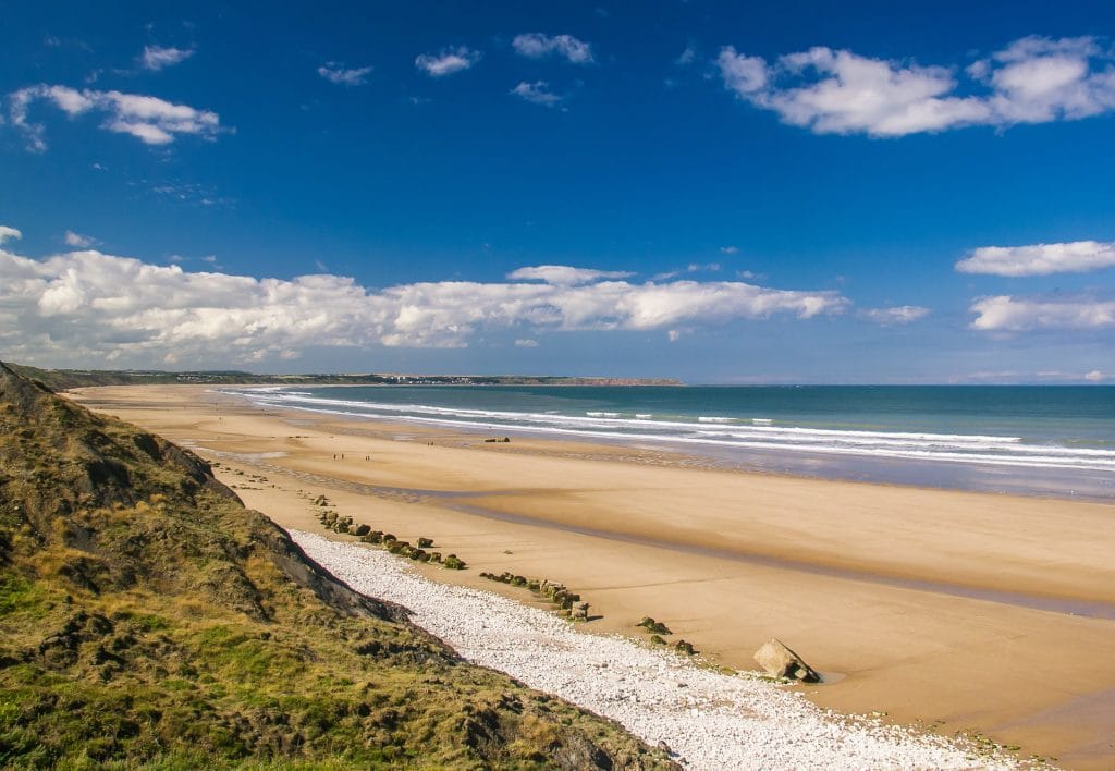 A wide, sweeping view of Filey Beach in North Yorkshire with golden sand.