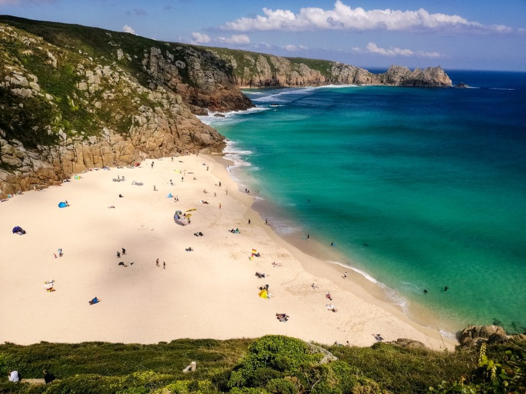 Porthcurno Beach Cornwall with golden sand and clear blue sea.
