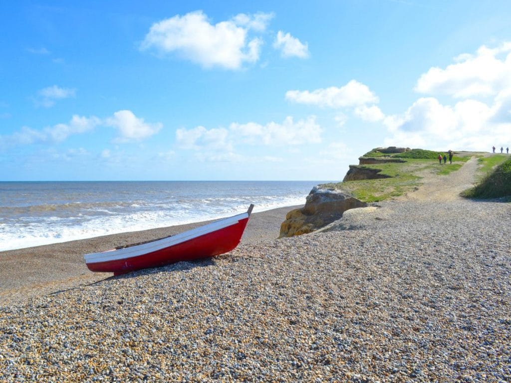 A red boat pulled up on the shingle beach at Weybourne