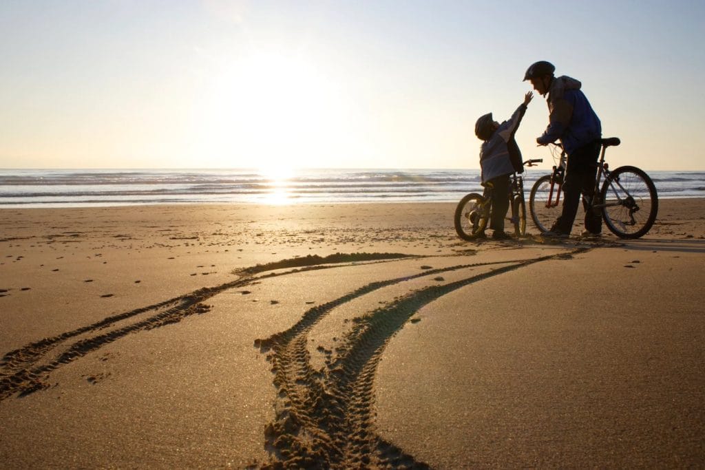Father and son on the beach with bikes