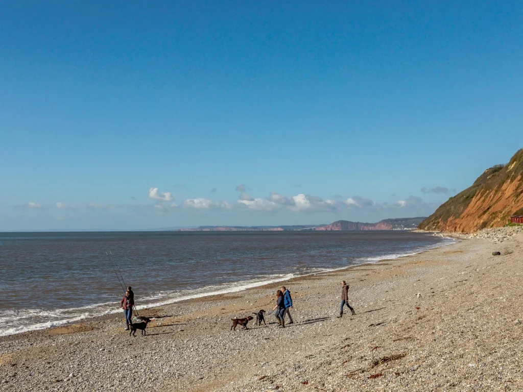 People walking a dog on Branscombe Beach in Devon