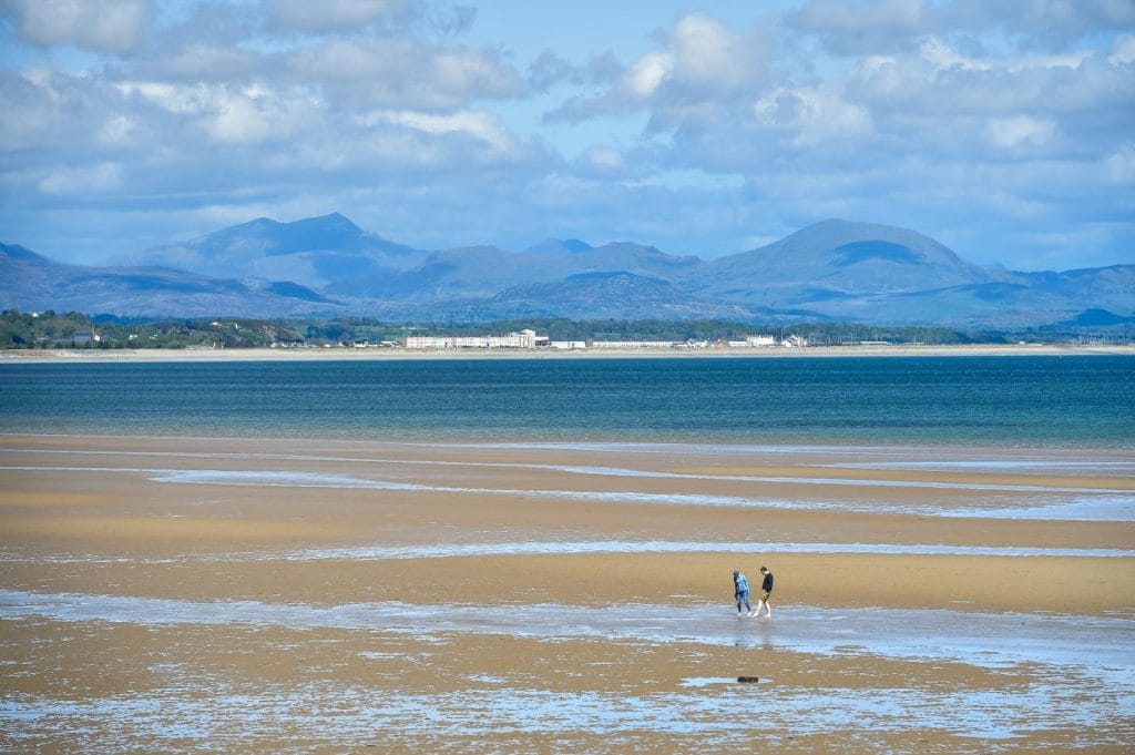 A couple walking on Llanbedrog Beach in North Wales