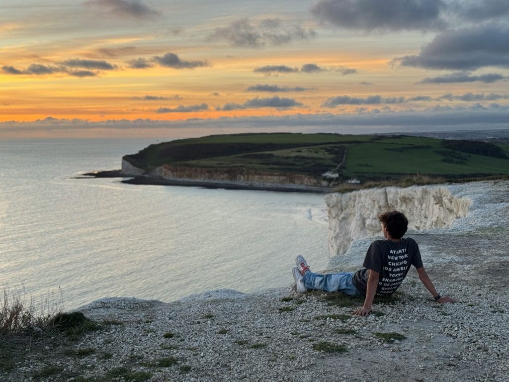 Boy sitting on the cliffs overlooking Seven Sisters in East Sussex