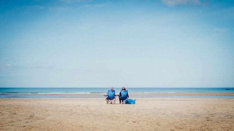 Couple sitting on the beach staring out to sea