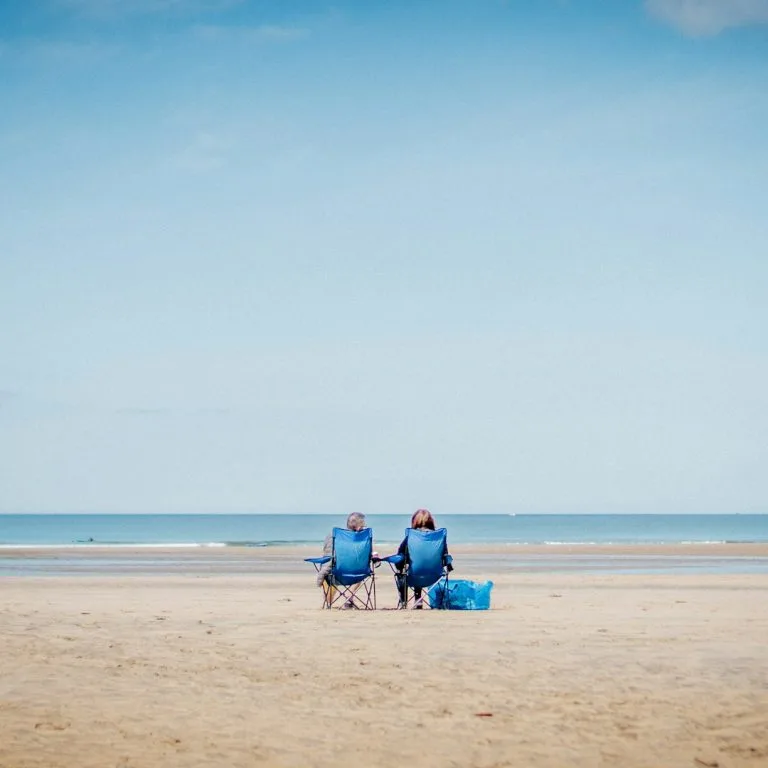 Couple sitting on the beach staring out to sea