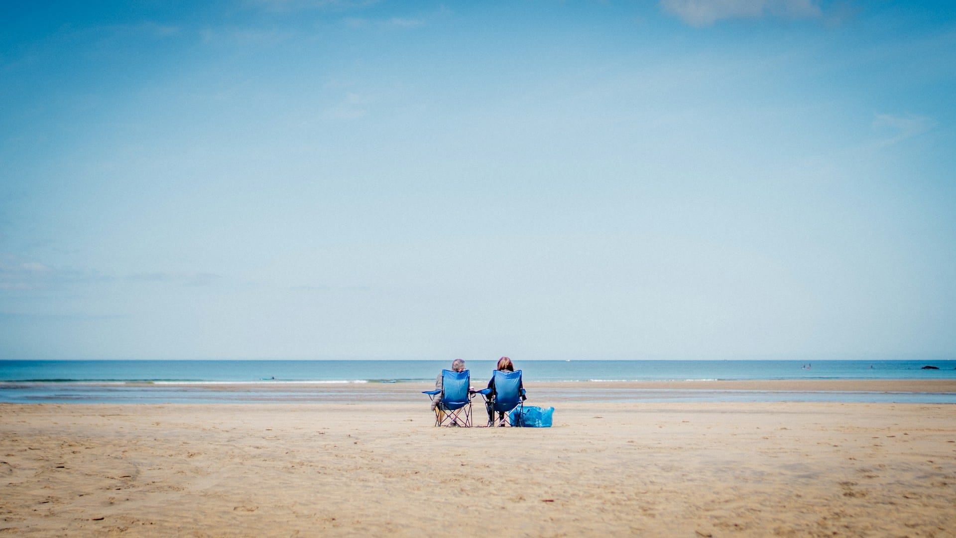 Couple sitting on the beach staring out to sea