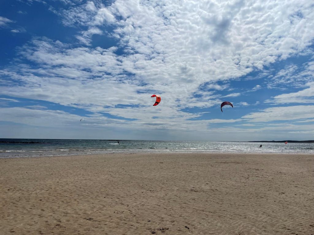 Two kite-surfers playing on Beadnell Beach, Northumberland.