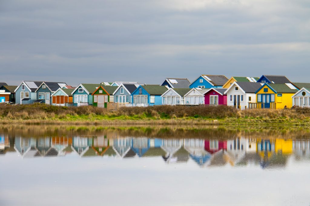 Row of colourful beach huts at Mudeford Sandbank, Bournemouth, UK.