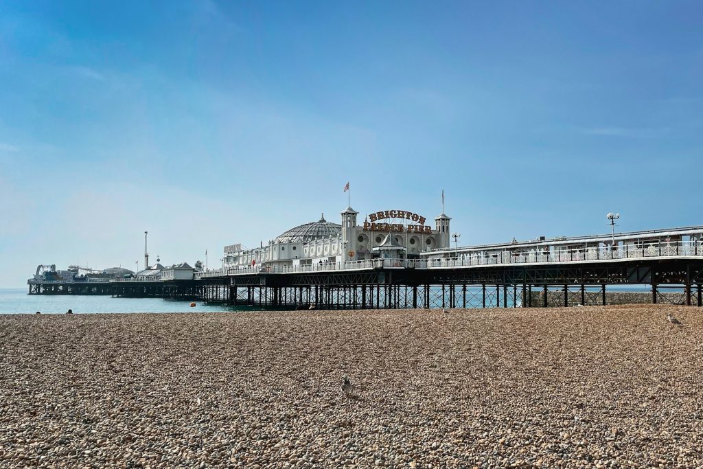 The iconic Brighton Pier and shingle beach on a sunny day.