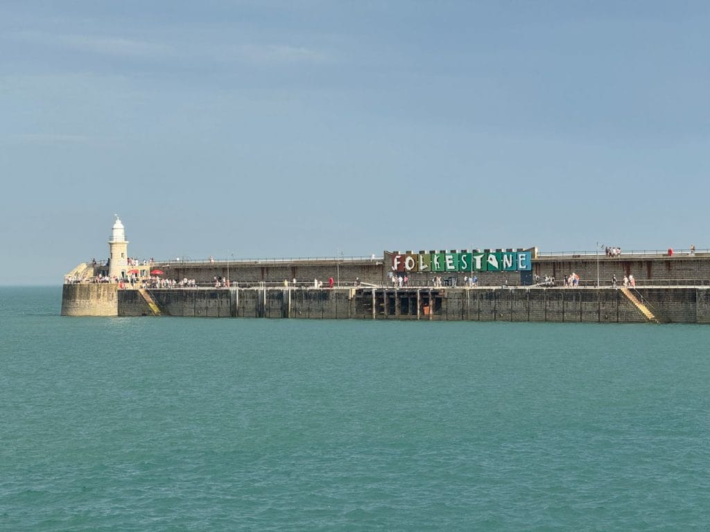 A view of Folkestone Harbour and lighthouse on a sunny day in Kent.