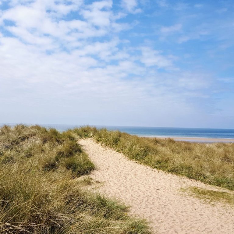 Dreamy view of sand dunes and beach in Angle, Wales on a summer's day.