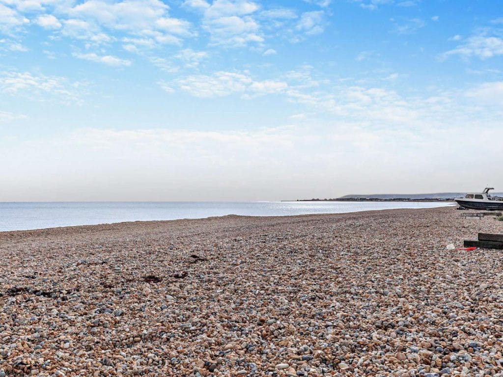 The pebble beach at Pevensey Bay with an old boat resting on the shore