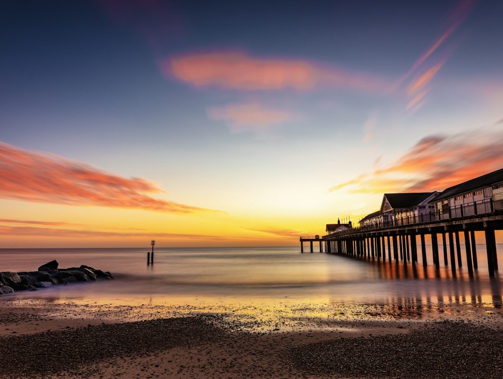 Shingle and sand beach and pier at Southwold, Suffolk at sunset.