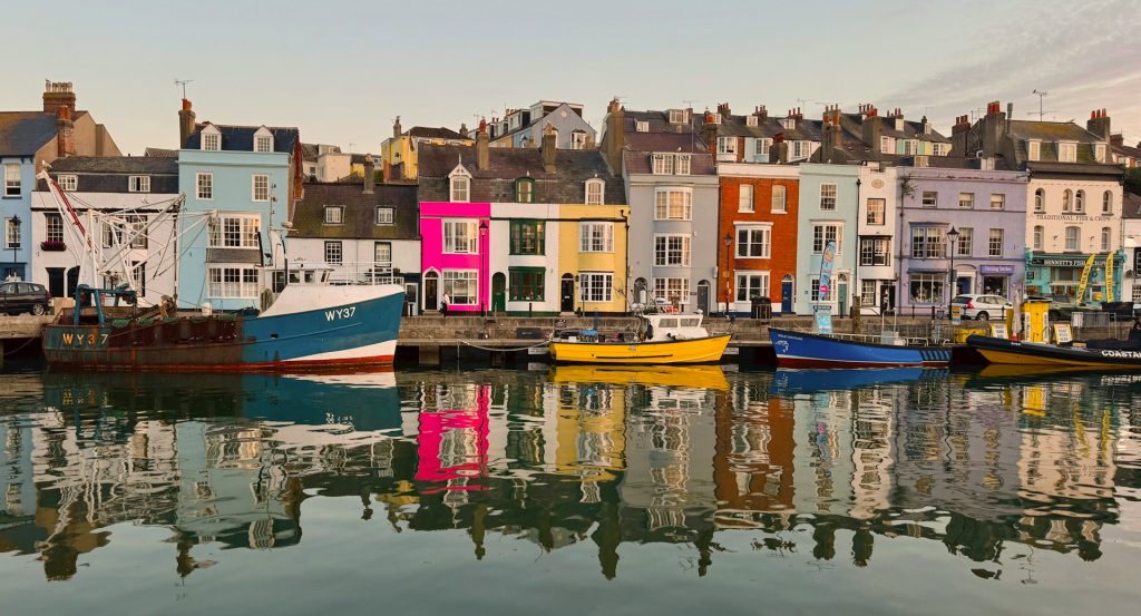 The reflection of terraced houses and boats on the water at Weymouth harbour, Dorset.