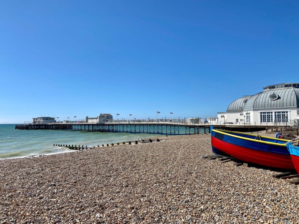 The pier at Worthing on a sunny day with boats nearby