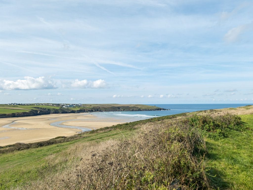 Grassy hills with walking tracks overlooking a sandy beach in Newquay