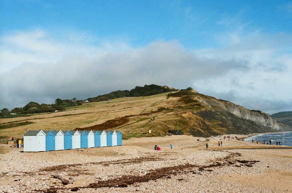 Colourful beach huts on Charmouth beach with cliffs in the background.