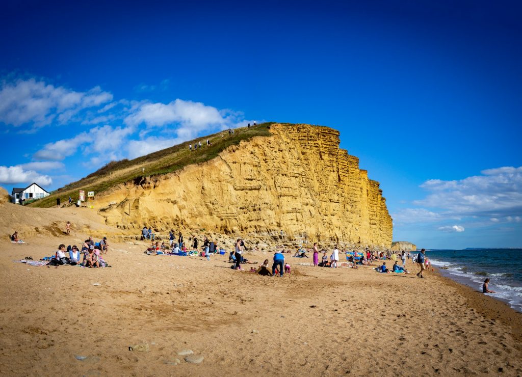 People on the beach and in the sea at West Bay on the Jurassic Coast.
