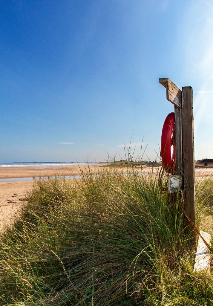 Orange life buoy on the beach at Alnmouth, Northumbrian Coast.