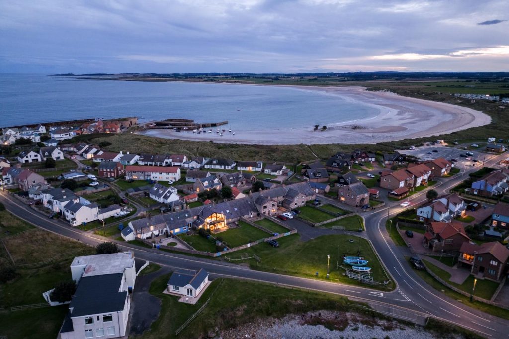 A view of Beadnell Bay at dusk showing the lights of the seaside cottages.