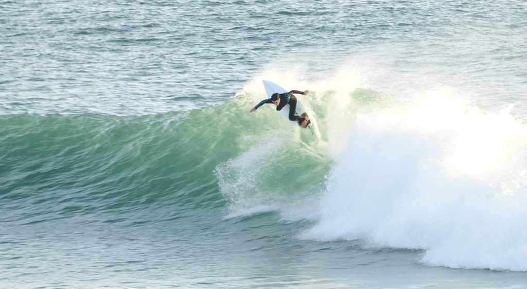 Surfer performing a re-entry on a wave at Belhaven Bay, Scotland, UK.