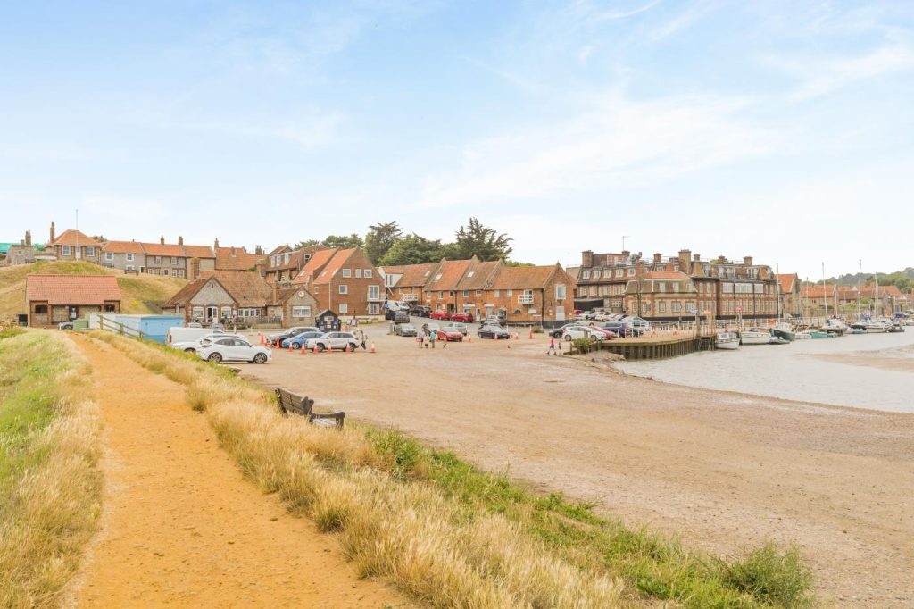 The seafront and beach at Blakeney with boats moored in the harbour.