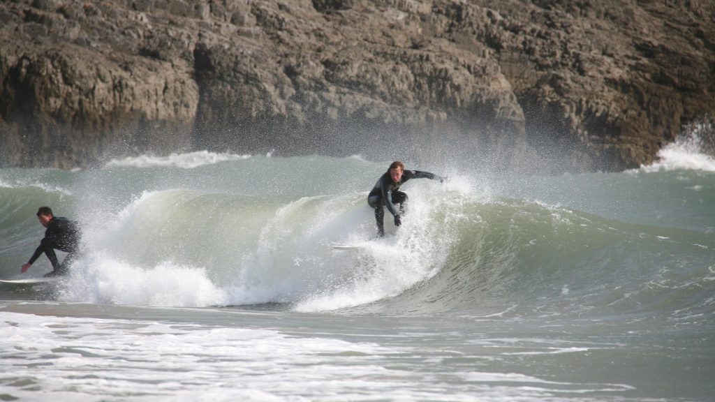 Two surfers at Caswell Bay, Gower, Wales, UK.