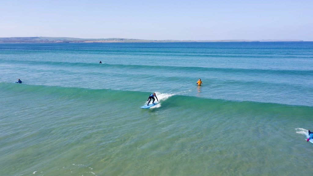 Man riding a small wave at Dunnet Bay in crystal clear water, Scotland.