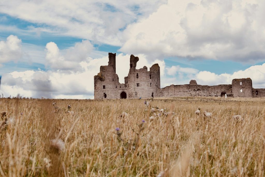 Looking across brown fields at Dunstanburgh Castle in Northumberland, UK.