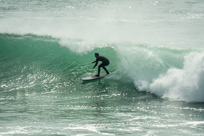 Surfer enjoying a perfect wave in Freshwater West, Pembrokeshire.