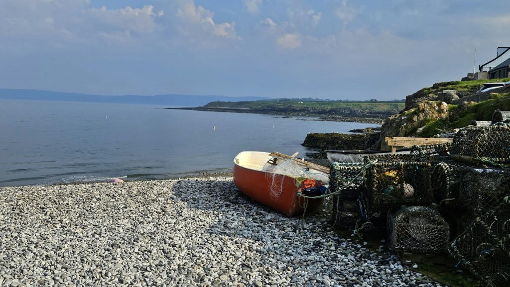 Fishing boat and nets on the small pebble beach in Moelfre, Anglesey.