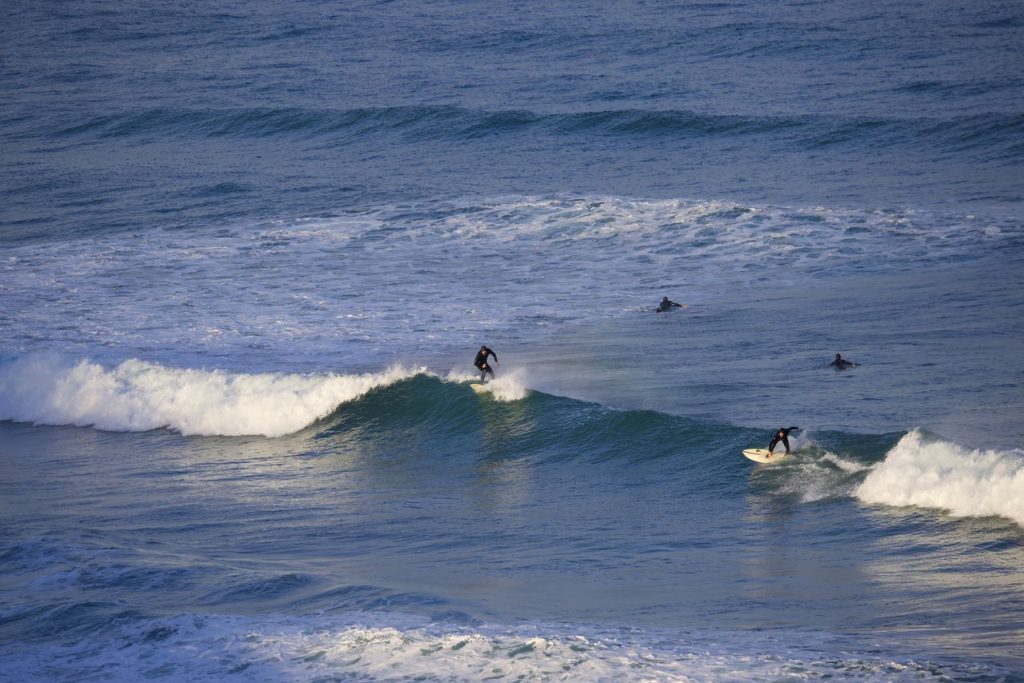 Surfer riding a small wave at Watergate Bay in Cornwall, UK.