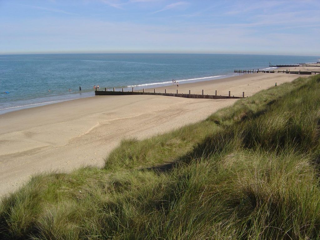 View of wooden groynes on Winterton-on-Sea beach from the grassy dunes.