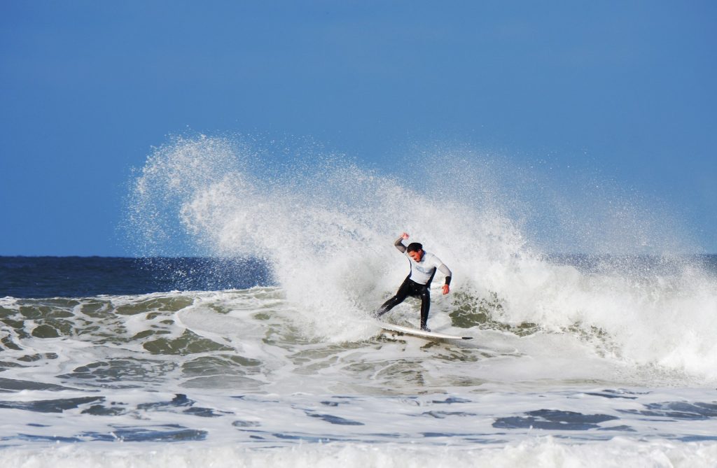 Surfer riding a wave on Woolacombe Beach, Devon.