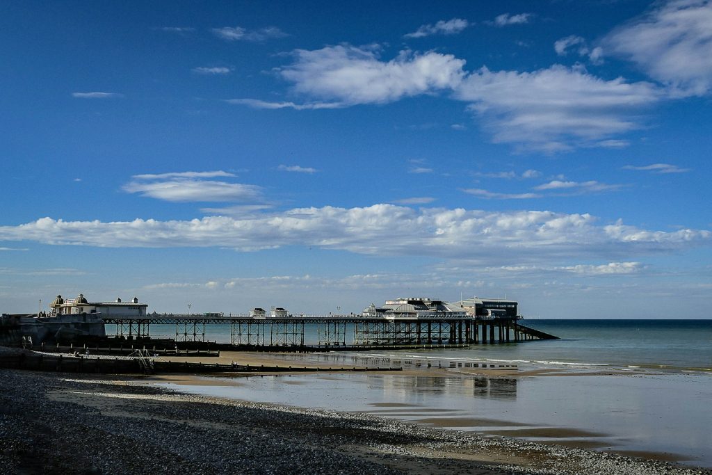 Side view of Cromer Pier under a blue and cloudy sky.