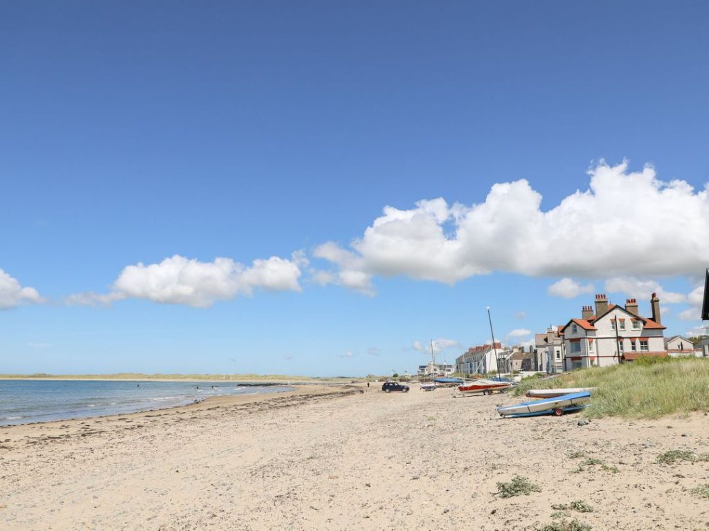 Rhosneigr beachfront with boats moored on the sand.