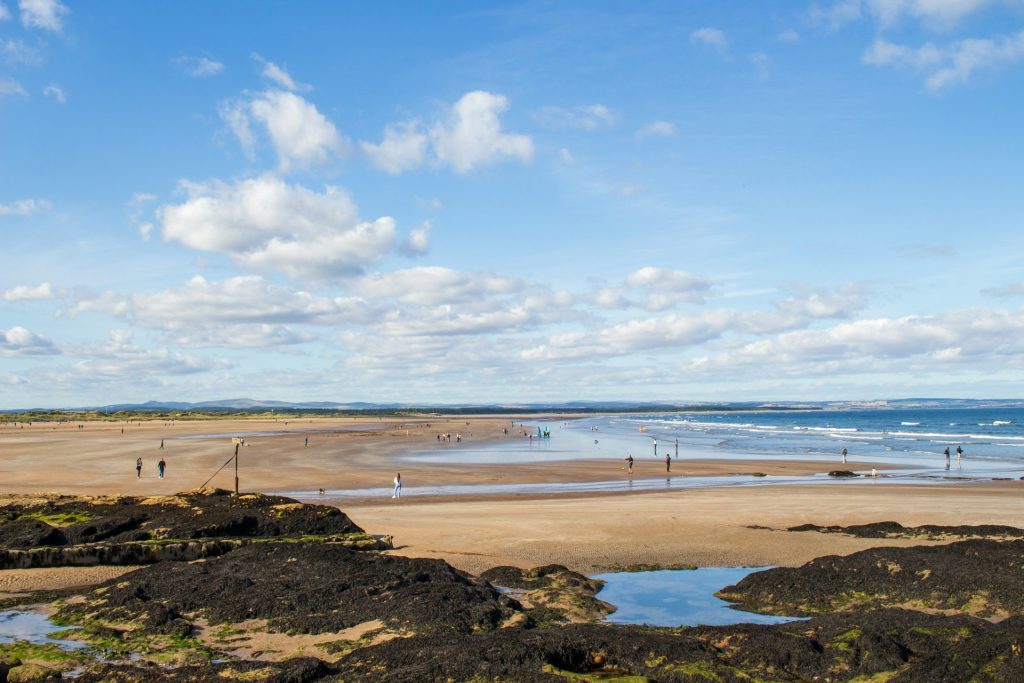 People walking on the sandy beach at St Andrews, Fife, Scotland.