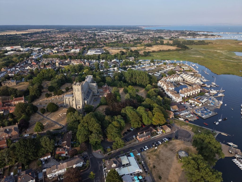 Aerial view of Christchurch Priory and the surrounding marina and sea.