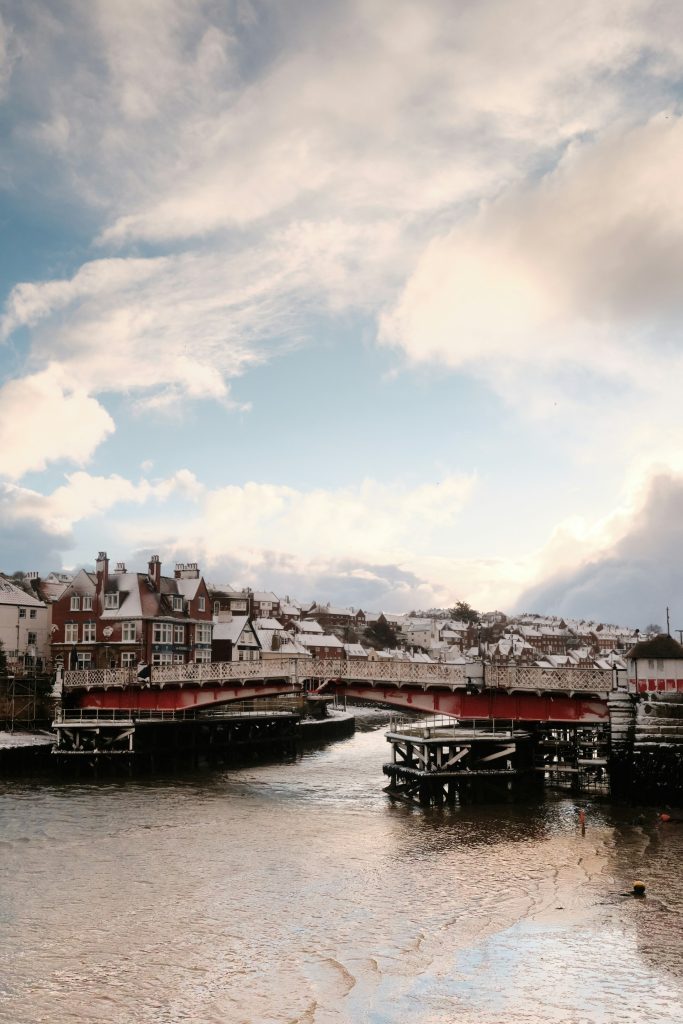 Bridge near Whitby Harbour in winter with seaside cottages dotted around.
